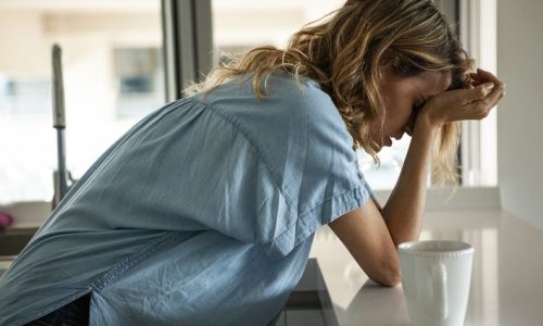 Potrait of stressed woman with head in hands standing indoors during daytime